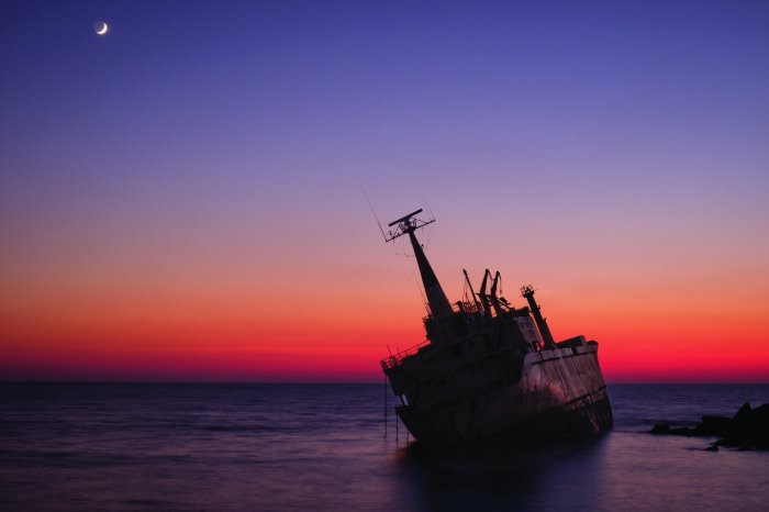 Papier peint  Épave de navire en mer au coucher du soleil