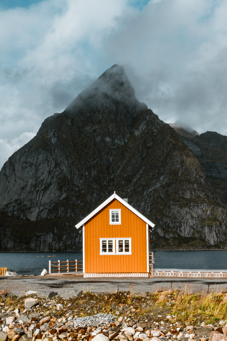 Poster  Une maison orange au milieu des montagnes et de l'océan