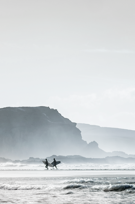 Poster  Des surfeurs avec leurs planches sur une plage bordée d'une falaise