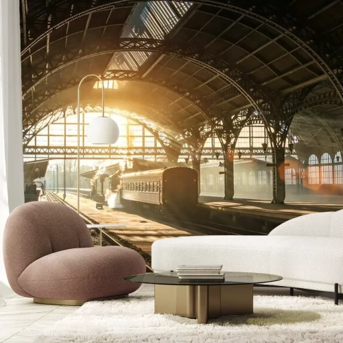 Papier peint  Ancienne gare avec un train et une locomotive sur le quai en attente de départ. Les rayons du soleil du soir dans les arcs de fumée.