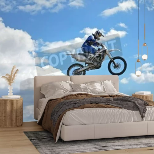 Papier peint  Motocross rider standing on the motorcycle MX is flying over the hill on a background of blue sky