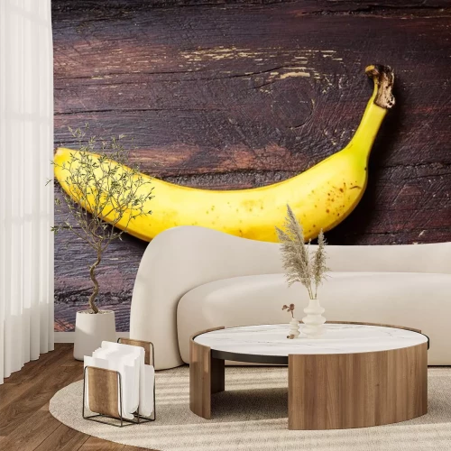 Sticker  Une banane posée sur une surface en bois sombre