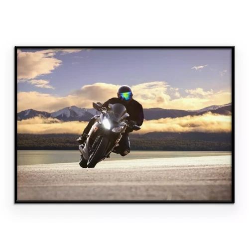 Poster  Un motard roule avec des montagnes en arrière-plan, parmi les nuages.